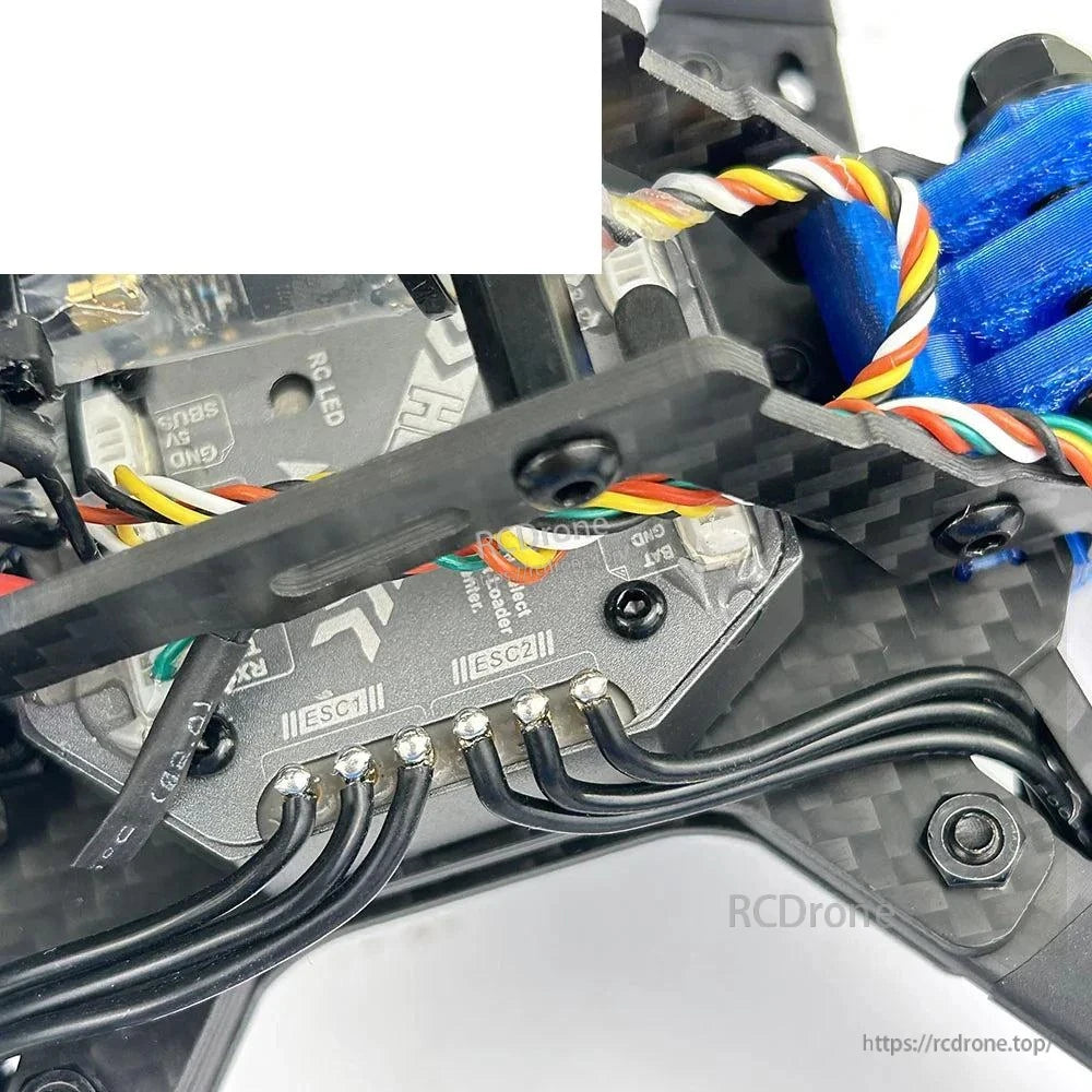 Close-up of flight controller wiring and ESC solder pads inside carbon frame