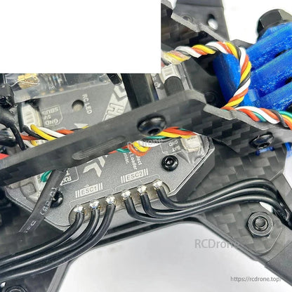 Close-up of flight controller wiring and ESC solder pads inside carbon frame