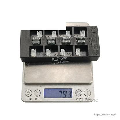 Board on digital scale with 79.3 g display, showing eight balance connector slots on the top surface