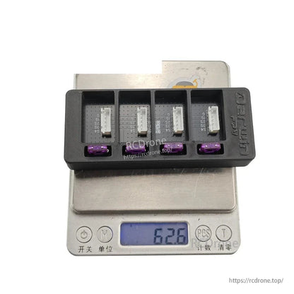Charger board on digital scale showing weight reading 62.8 g, with four bays and purple fuses