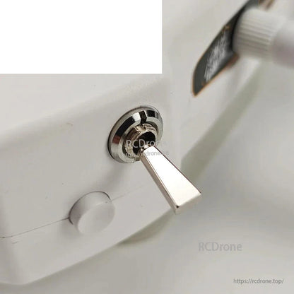 Metal toggle switch close-up on transmitter shoulder with adjacent round button
