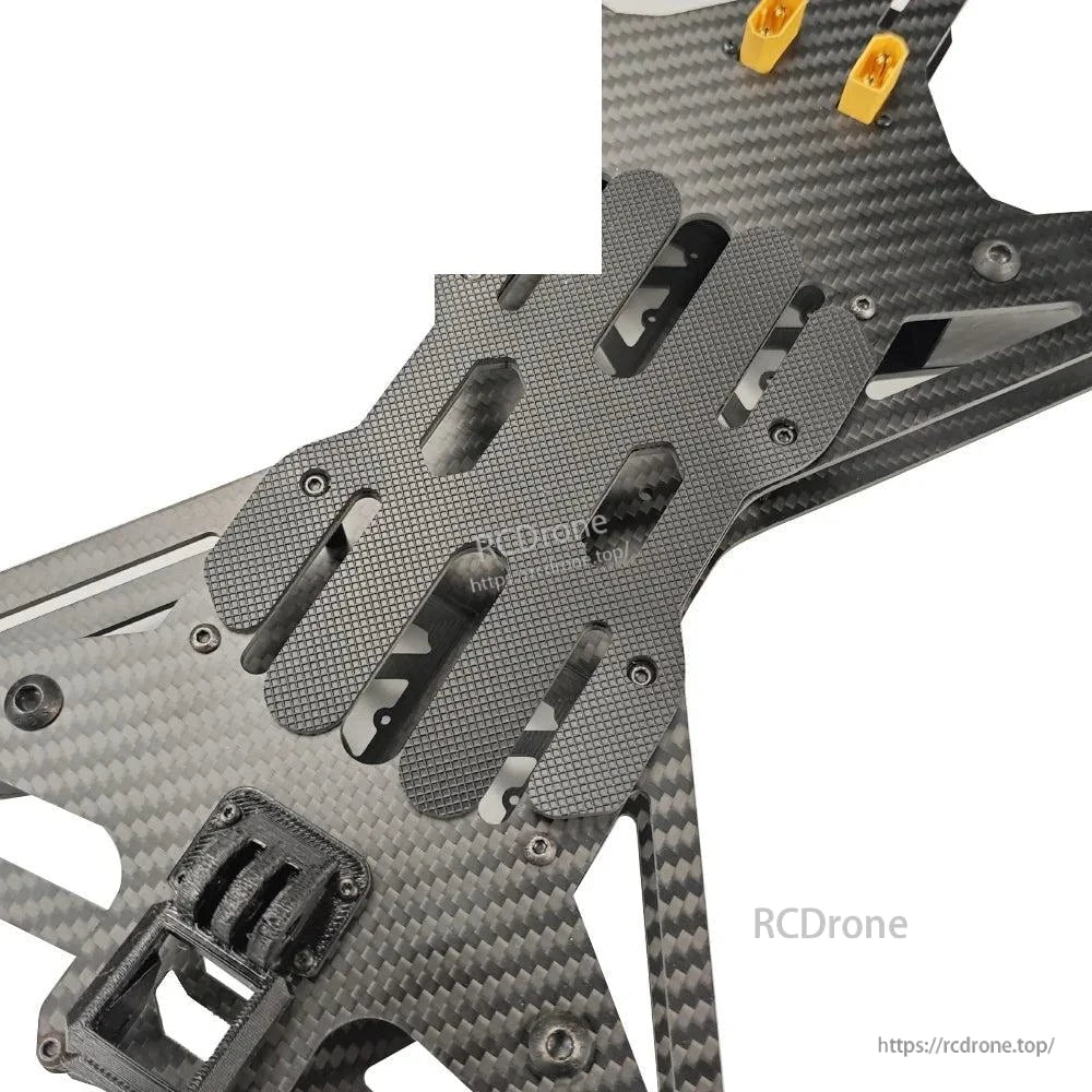 Center deck close-up showing textured battery pad plate and mounting slots on carbon frame