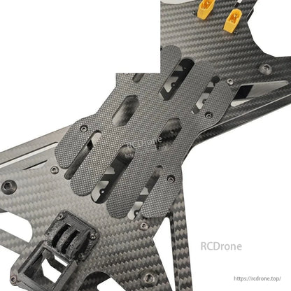 Center deck close-up showing textured battery pad plate and mounting slots on carbon frame