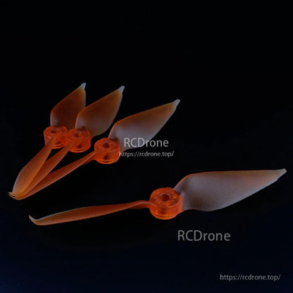 Translucent orange 2-blade FPV racing propeller set, four stacked props plus one laid flat