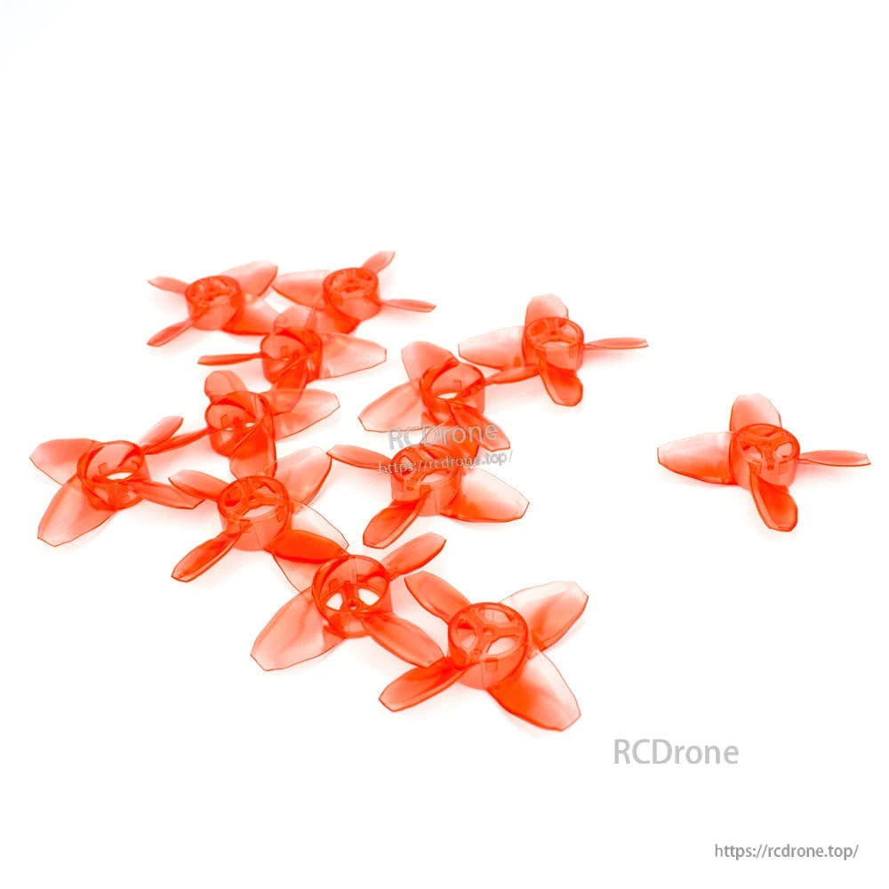 Assorted translucent red 4-blade micro quad propellers spread out on white background