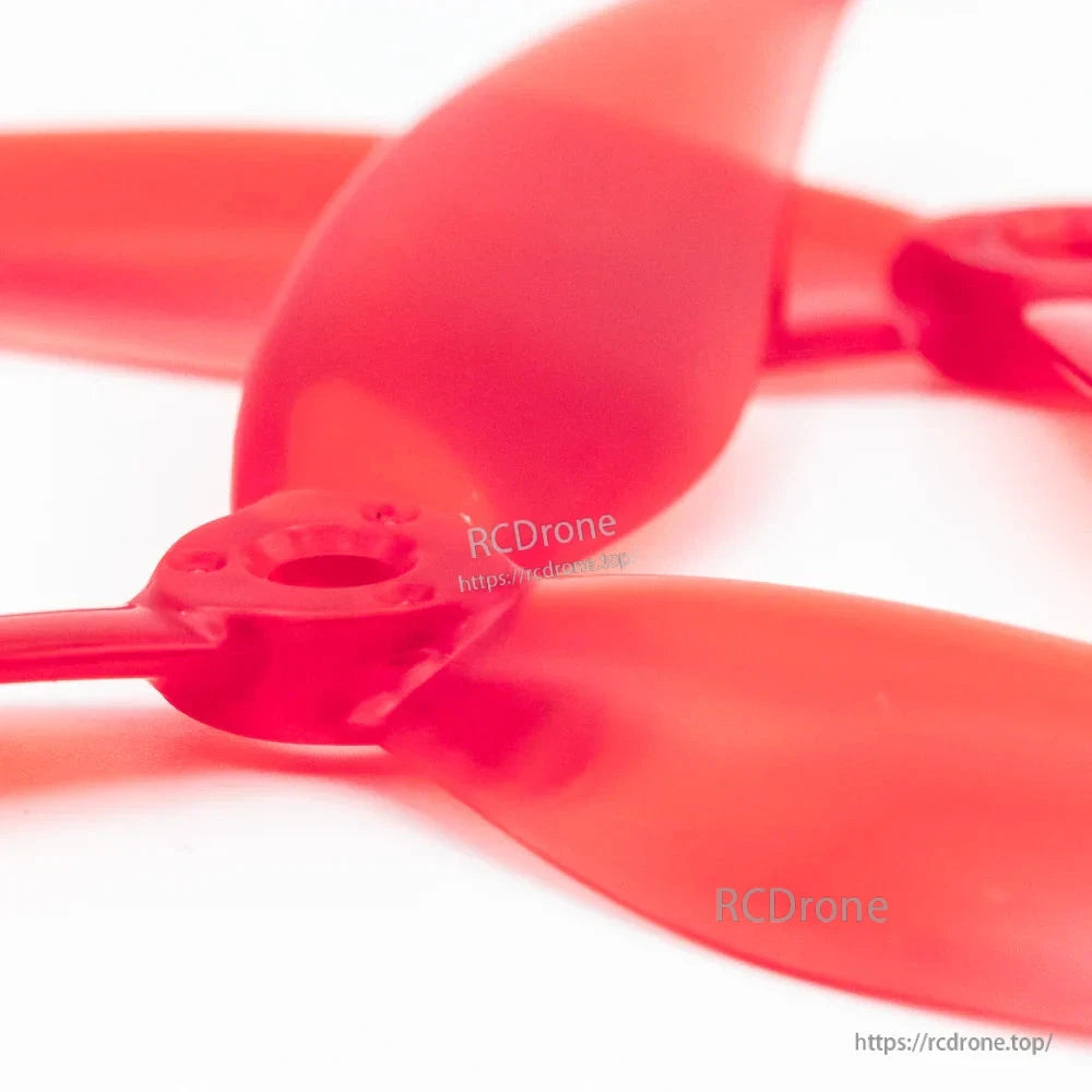 Close-up of EMAX Avia 7035 propeller hub and screw holes on red 3-blade FPV prop