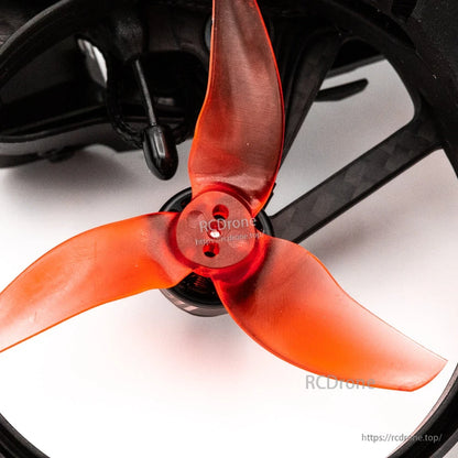 Close-up of orange tri-blade propeller mounted in ducted frame, showing hub and blade shape