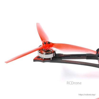 Close-up of a motor and red tri-blade propeller mounted on the carbon fiber arm