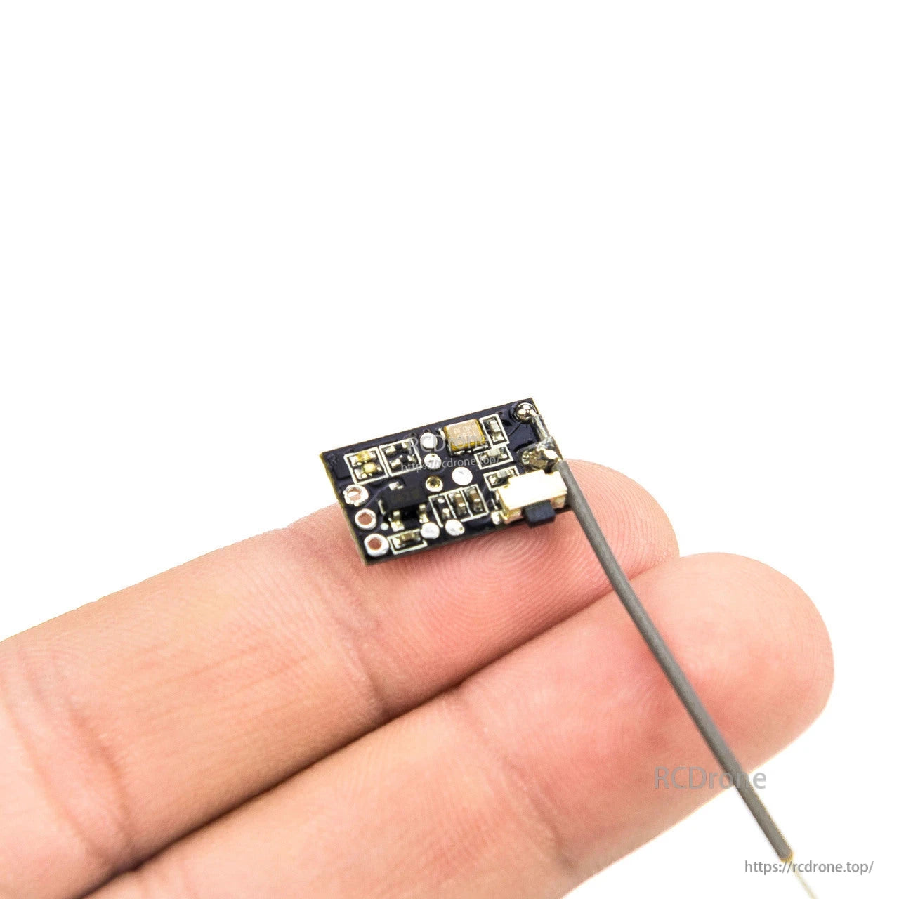 Close-up of receiver PCB on hand showing solder pads and connector edge with antenna attached