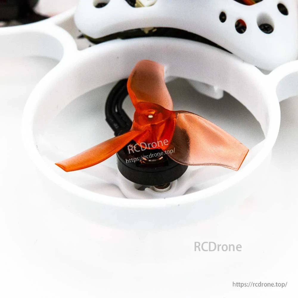 Close-up of orange three-blade propeller inside white duct with motor and wiring