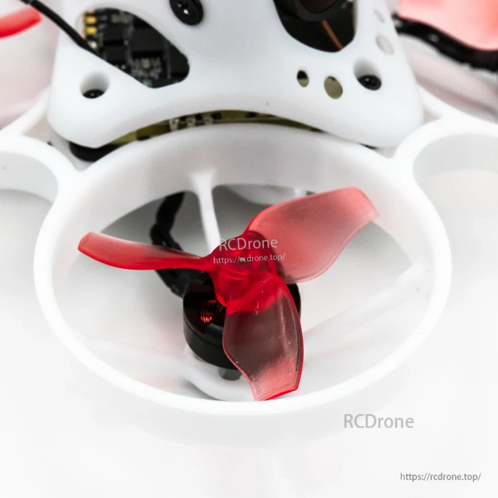 Close-up of red tri-blade propeller and motor inside white ducted whoop prop guard