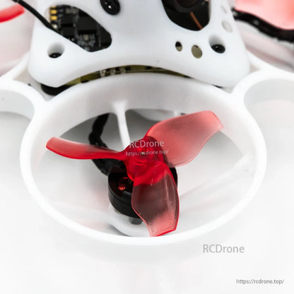 Close-up of red tri-blade propeller and motor inside white ducted whoop prop guard