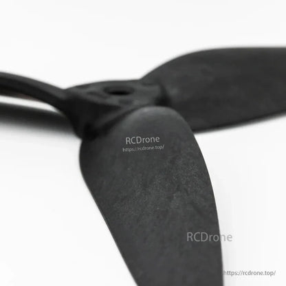 Macro close-up of propeller blade surface texture and hub edge on black 3-blade drone prop