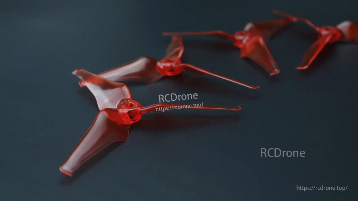 Red tri-blade FPV drone propellers laid out as a set, CW and CCW rotation pair for 5-inch quads