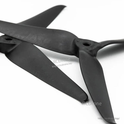 Angled view of two black 8043-3 tri-blade FPV drone props overlapping, showing blade shape and hub