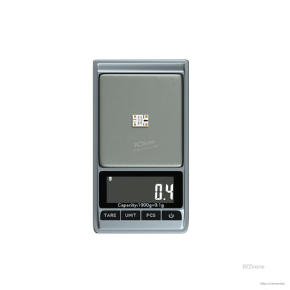 FLYWOO O4 1S 5V/3A BEC, FLYWOO O4 1S BEC 5V module on a digital scale, showing labeled solder pads for GND, +5V, and input