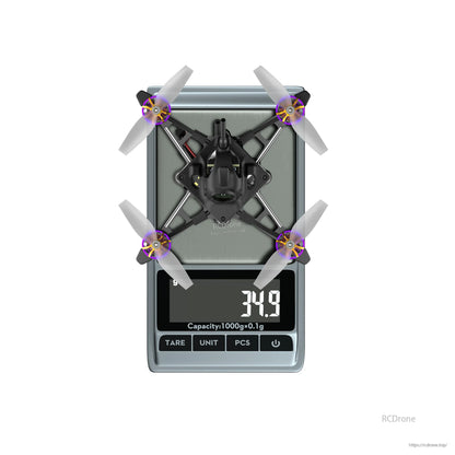 Tiny quadcopter drone with four propellers on a digital scale showing 34.9 g weight reading