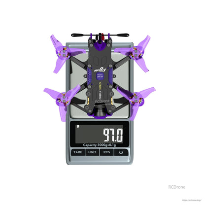 Top-down view of a micro FPV drone with purple propellers on a digital scale reading 97.0 g