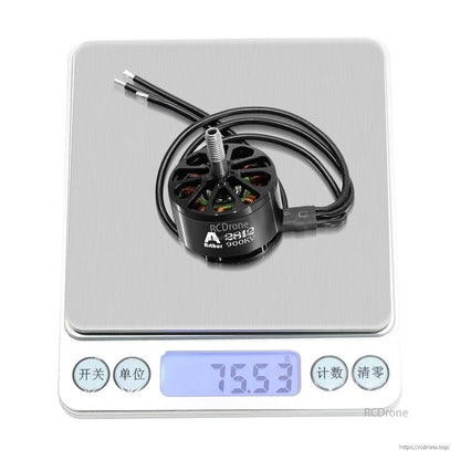 Flashhobby A2812 900KV brushless motor with three wires and threaded shaft on a digital scale reading 75.53