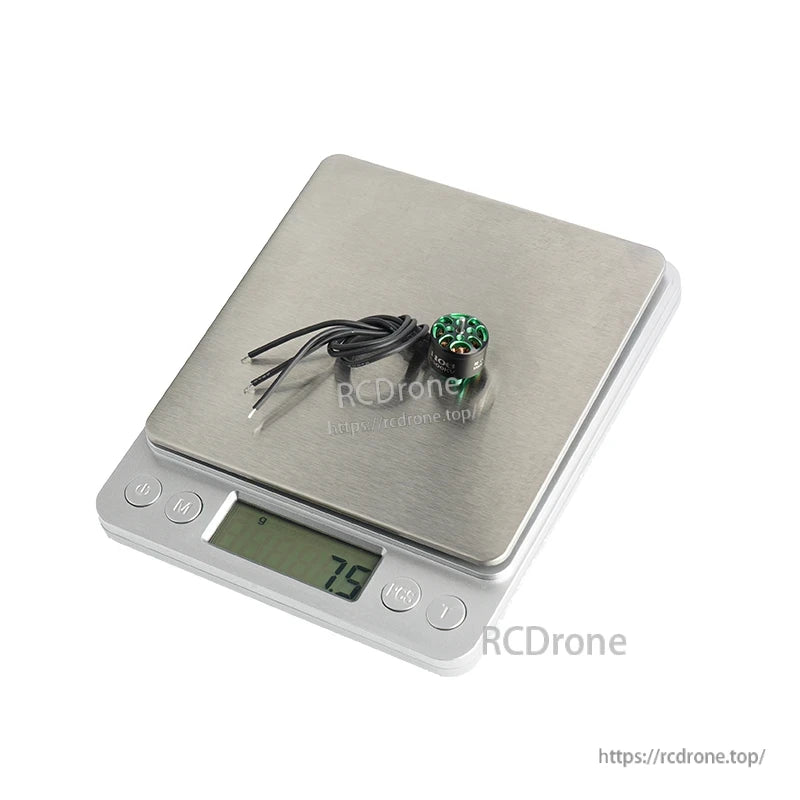 Small Flashhobby A1106 brushless drone motor with three wires sitting on a digital scale reading 7.5 g