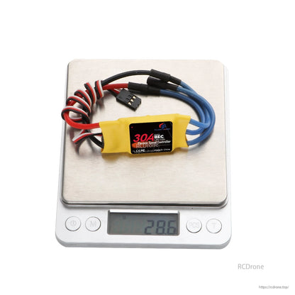 Flashhobby Spaceman 30A ESC with yellow heatshrink, blue motor wires, and 3-pin signal lead on a scale (28.6 g)