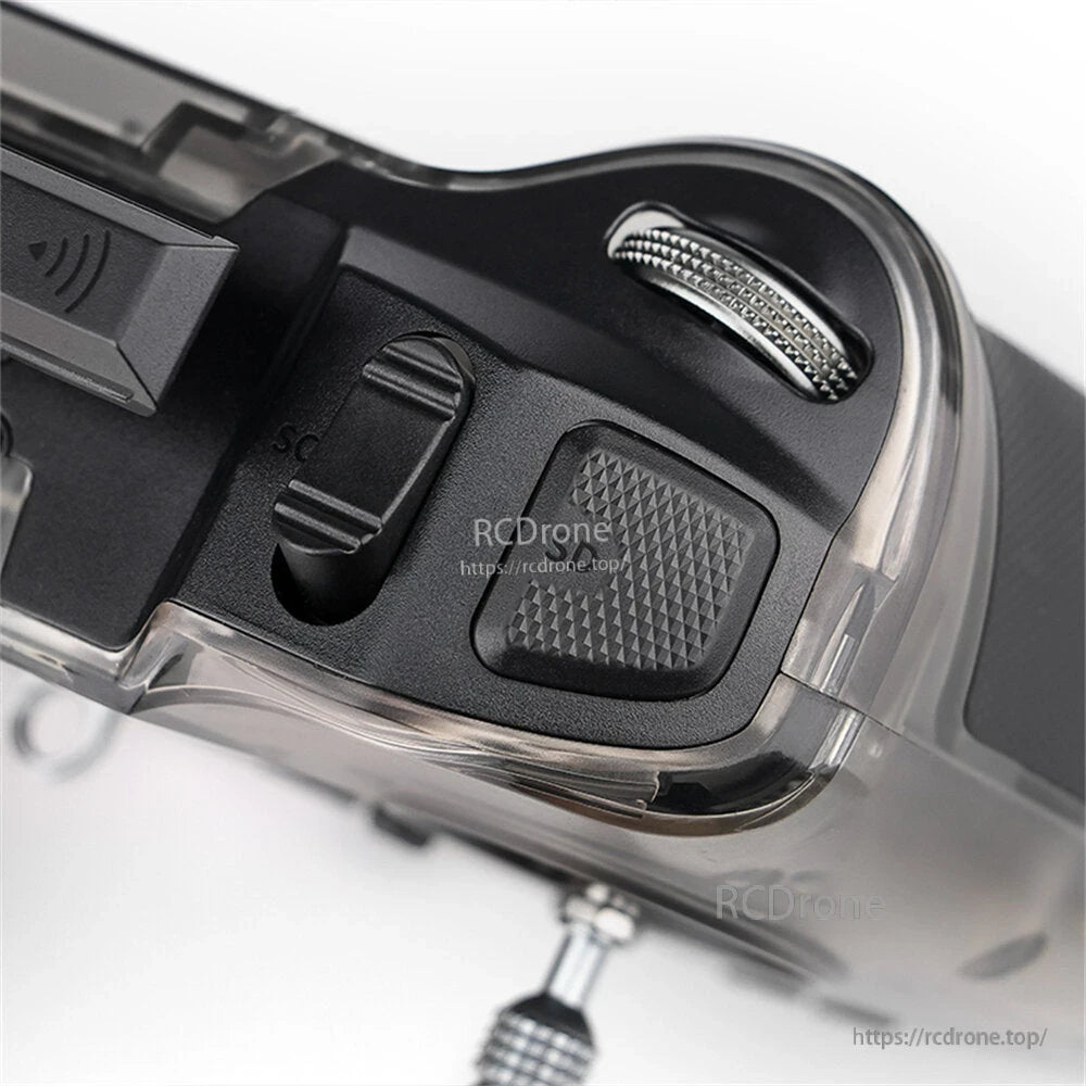 Top shoulder close-up showing SC slider switch, textured button, and metal dial/wheel on the corner