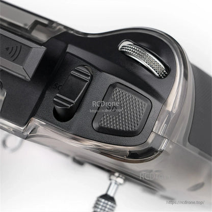 Top shoulder close-up showing SC slider switch, textured button, and metal dial/wheel on the corner