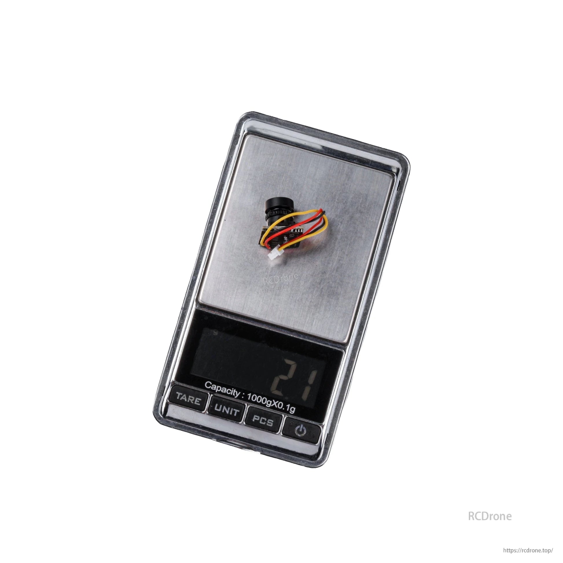 Flywoo 1S Nano Camera, Compact nano FPV camera module with lens and multi-wire connector placed on a digital pocket scale