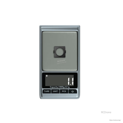 Digital pocket scale with a small square FPV camera part on the platform, displaying 1.1 g.