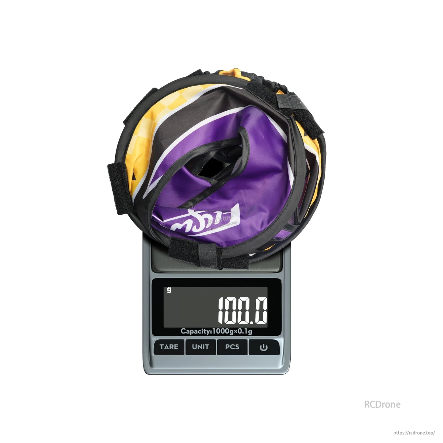 Folded Flywoo FPV halo circle race gate secured with Velcro straps on a digital scale reading 100.0 g
