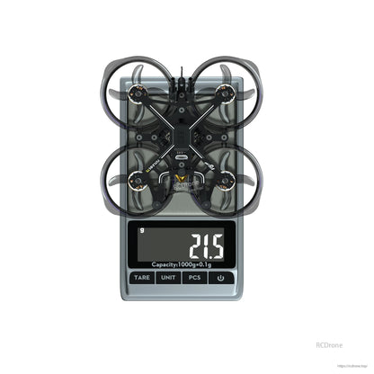 Flywoo FlyLens 75 whoop-style FPV drone on a digital scale with ducted prop guards, reading 21.5 g
