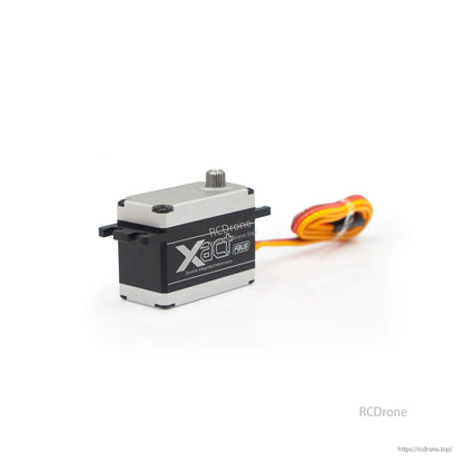 Angled close-up of Xact FBUS servo showing output shaft, CNC aluminum case edges, and orange wire loom