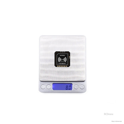 GEPRC GEP-M10 series GPS module on a digital scale showing 8.0g, with antenna side marked “this side up”