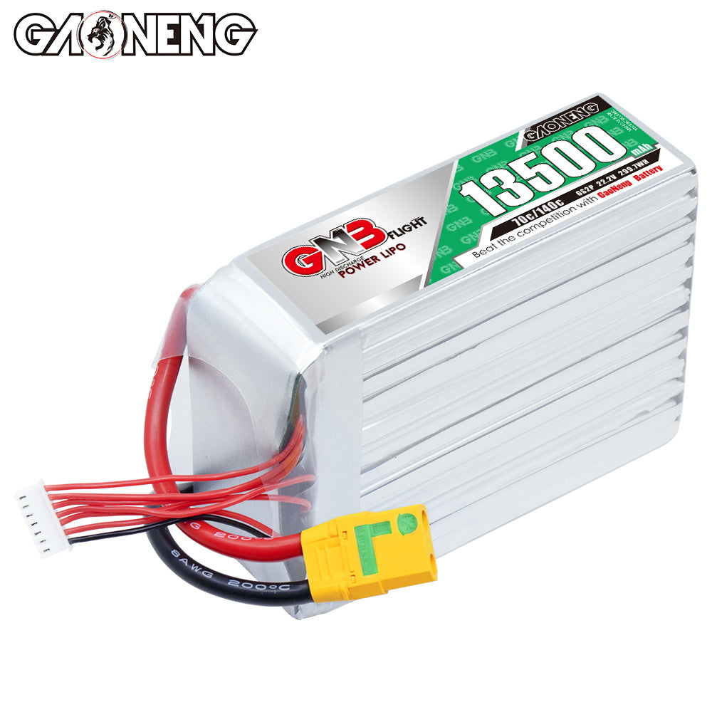 Angled top view of GNB 13500mAh battery showing silver case fins, label, XT90S plug, and balance lead