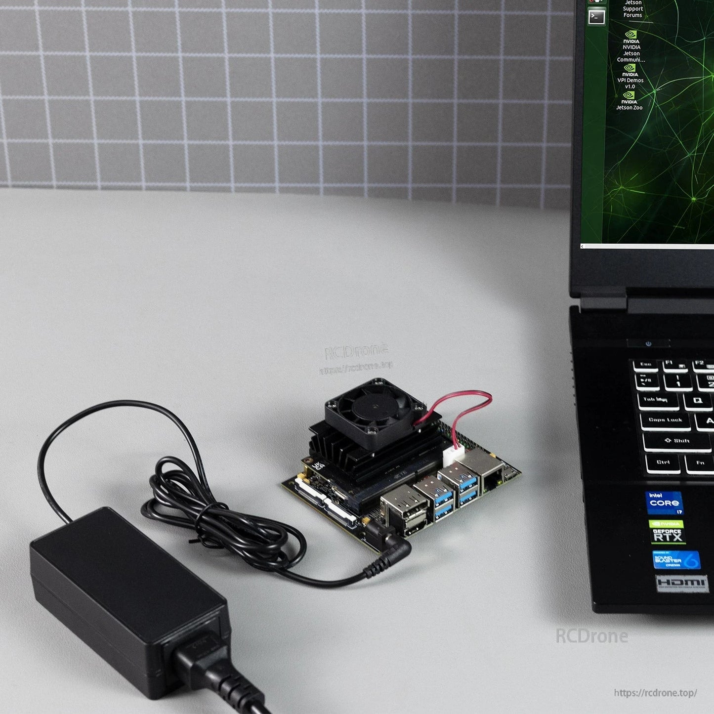 DC power adapter connected to a small development board on desk next to a laptop, use-case setup