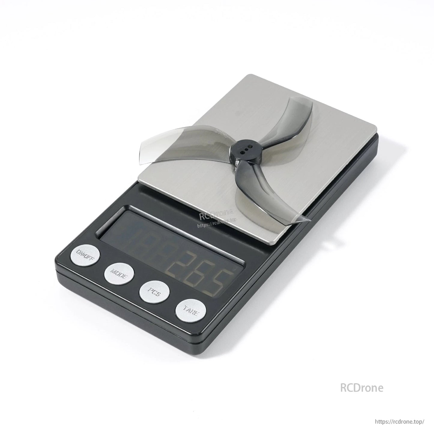 Single 3-blade FPV drone propeller resting on a digital scale for weight reference