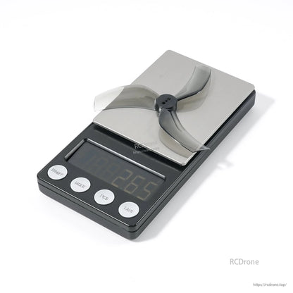 Single 3-blade FPV drone propeller resting on a digital scale for weight reference