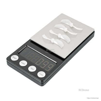 Four white 2-blade micro props arranged on a digital scale tray, angled view