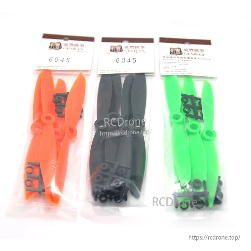 Retail packaging: three bagged Gemfan 6045 prop sets in orange, black, and green with adapter rings