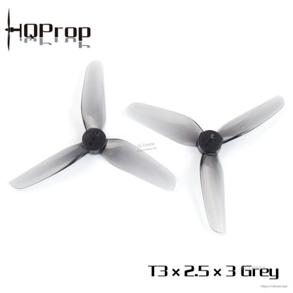 Pair of grey 3-inch tri-blade drone propellers laid out side by side, hubs facing up