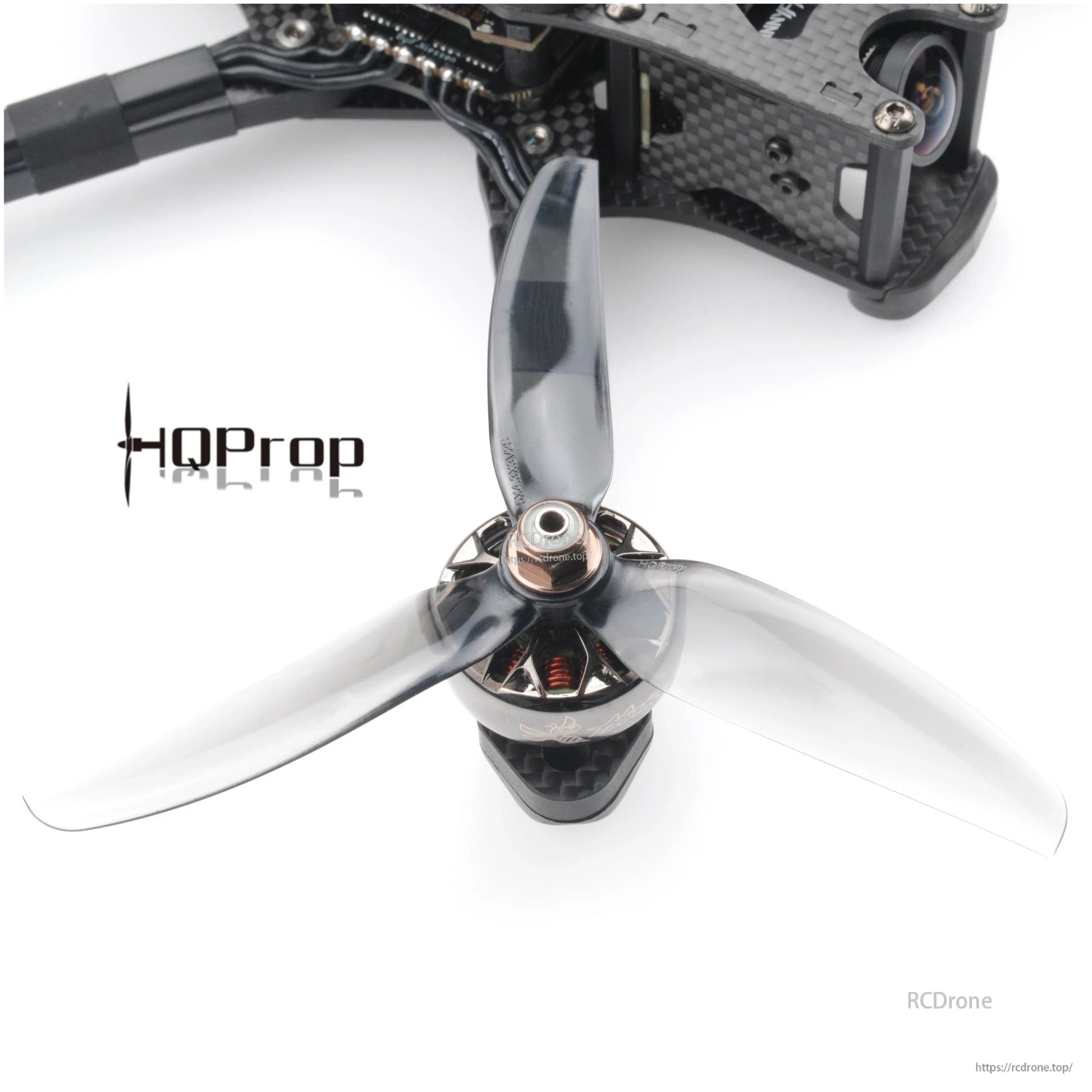Smoke gray 3-blade 5-inch prop installed on FPV quadcopter motor, top-down view