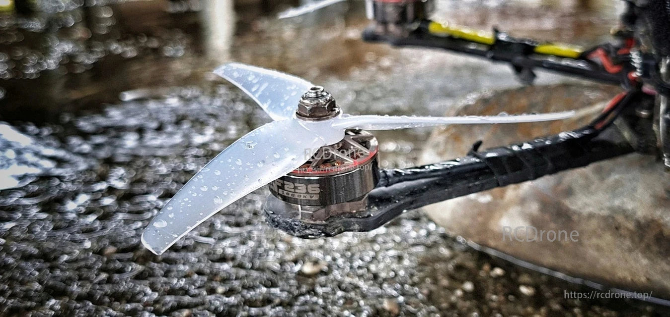 Close-up of translucent 3-blade propeller installed on FPV quad motor in wet conditions