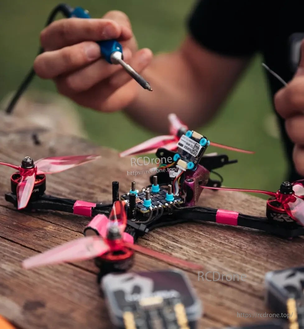 Technician soldering an FPV racing quad on a workbench during a build or repair