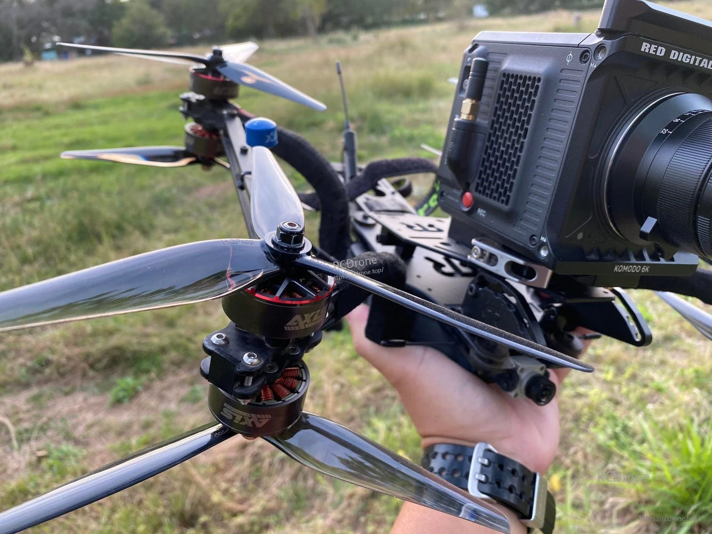 Grey 3-blade propeller installed on a quadcopter drone in outdoor field, close-up on motor mount