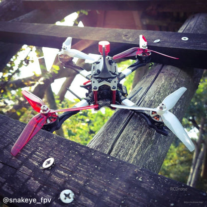 Red and white Ethix P4 3-blade props installed on a quadcopter frame outdoors, top-down view