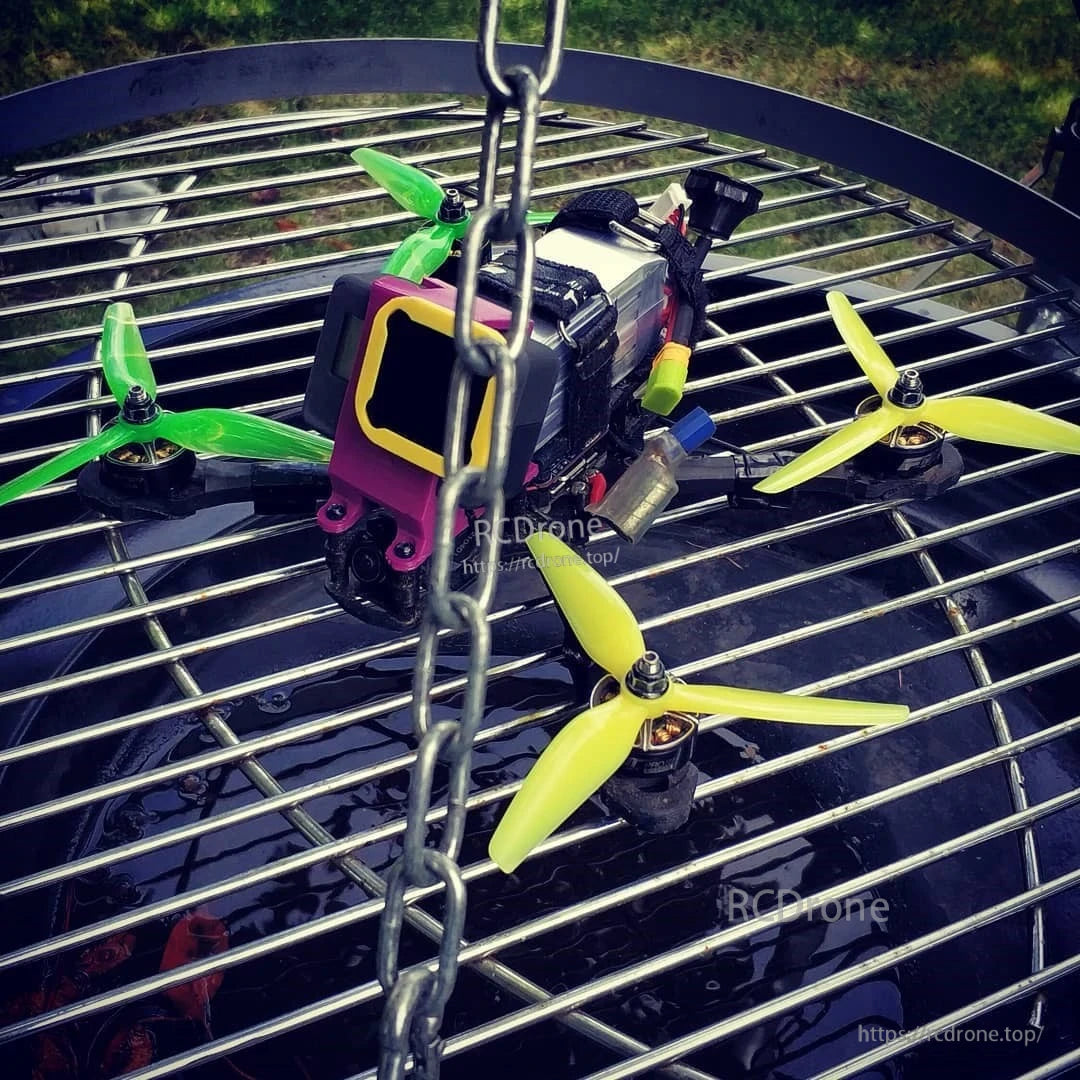 FPV quadcopter fitted with lemon-lime green and yellow 3-blade propellers on motors, outdoor close-up