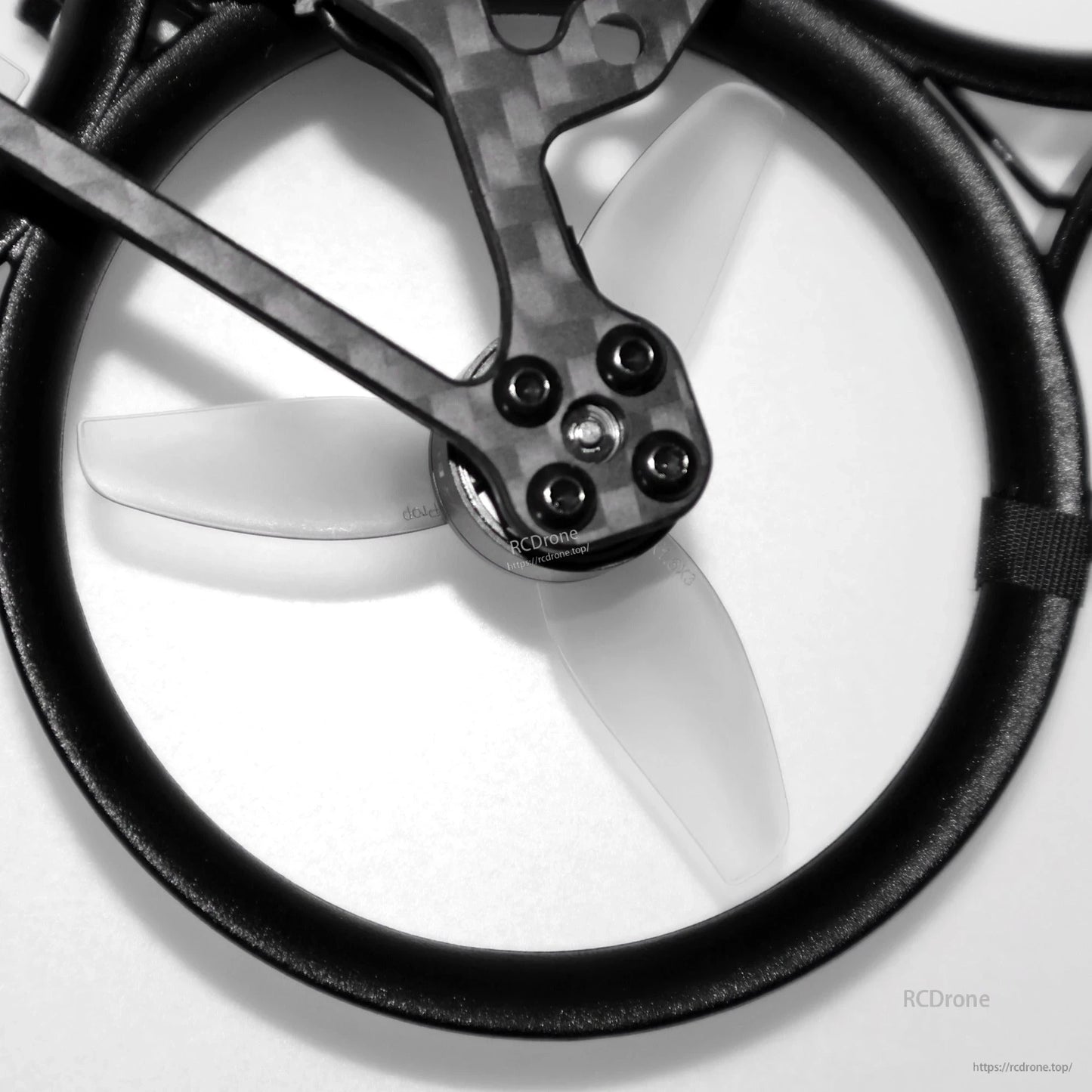 Installed grey 3-blade propeller inside circular duct guard on FPV drone arm, close-up detail