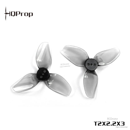 Angled view of two grey transparent 3-blade propellers with black centers, HQProp T2X2.2X3