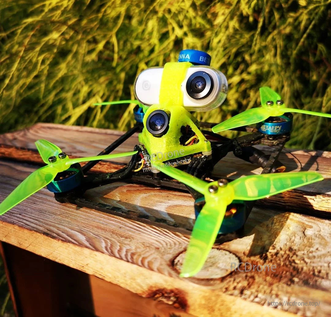 FPV quadcopter on wooden surface fitted with bright green tri-blade propellers, outdoor close-up