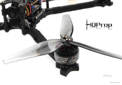 Grey 3-blade propeller mounted on FPV drone motor, close-up of hub and mounting screw